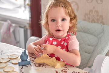Little girl in a pink polka dot apron plays with dough at the kitchen table.
Toddler learns baking through sensory play and early motor skills.
Cute child explores cooking at home, full of curiosity