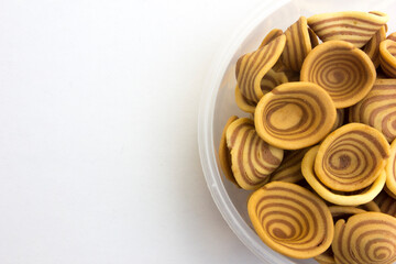 Brown spiral-shaped cookies isolated on white background. This cookie is commonly called “kuping gajah” in Indonesian.
