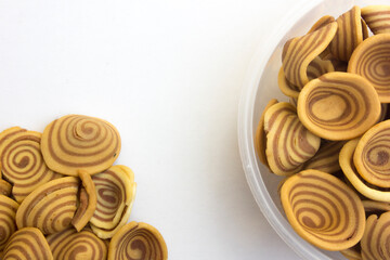 Brown spiral-shaped cookies isolated on white background. This cookie is commonly called “kuping gajah” in Indonesian.