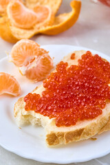 Sandwich with red caviar and tangerines. Traditional Russian treat on the New Year's table.