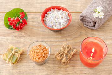 Towel with body care products and verbena flowers on the wooden background.