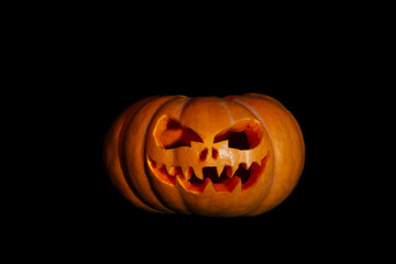 Fototapeta premium Halloween pumpkin with a scary face on a black background.