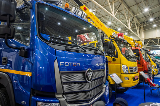 Ukraine, Kyiv - October, 16, 2025:Row of new Foton commercial trucks, including a blue utility vehicle with a crane, displayed at an indoor exhibition. Highlighting modern heavy machinery