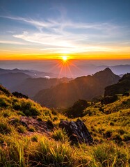 Fototapeta premium A vibrant sun sets over layered mountain peaks