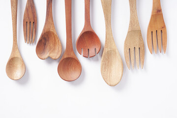 Wooden spoons and forks are stacked on a white background.