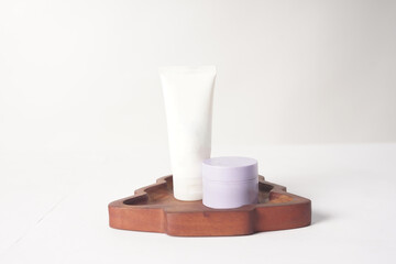 A sunscreen and a moisturizer are placed on a wooden tray against a white background.