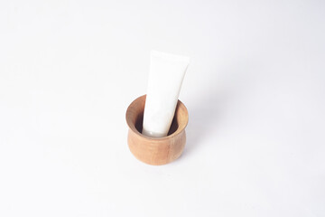 A sunscreen is placed inside a wooden bowl on a white background.