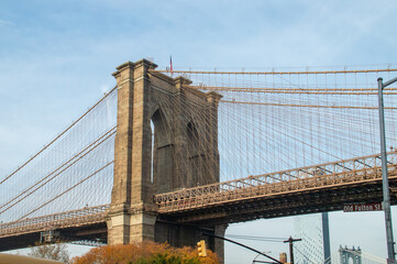 Fototapeta premium Brooklyn Bridge desde el cruce de la calle Fulton con la calle Furman. Detalles arquitectónicos del icónico puente que conecta Brooklyn y Manhattan en Nueva York, USA. 11 de noviembre de 2019.