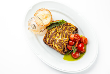 Gourmet sandwich with mustard drizzle, cherry tomatoes with basil, grated cheese in glass dish, and fresh green garnish on white plate. Elegant restaurant-style food presentation.