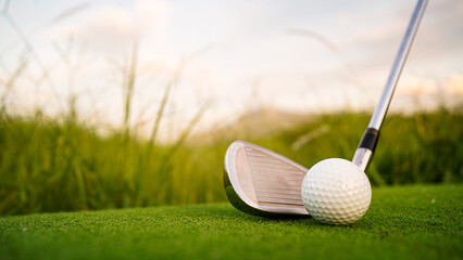 Golf clubs and balls on a green lawn in a beautiful golf course with morning sunshine.