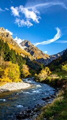 Obraz premium A river flows through a mountainous landscape under a blue sky