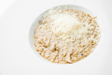 Creamy mushroom risotto served on a white plate, topped with finely grated cheese. Minimalist presentation, gourmet Italian cuisine, perfect for restaurant or food photography themes.