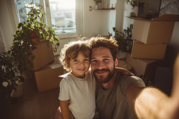 Smiling father and young son take a warm selfie among moving boxes in their new sunlit home, celebrating family bonding and fresh beginnings
