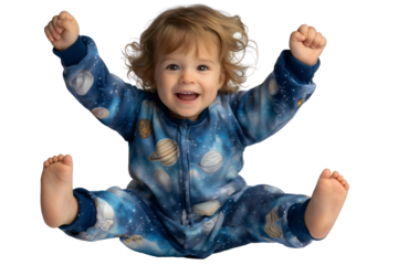 Excited happy toddler child in blue cosmic space planet pajamas sitting with arms raised celebrating on isolated transparent background.