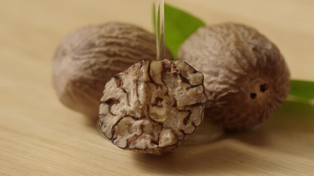 Close-up of cracked shea nuts doused with a stream of pure oil, styled for a skincare ingredient brand photography.