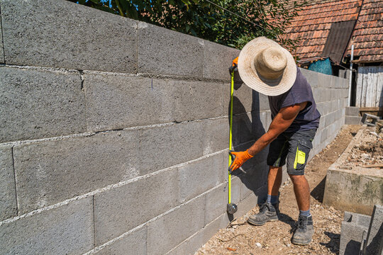 Construction worker measuring concrete block wall, building a new project with precision and accuracy