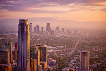 Fototapeta premium Golden hour over Los Angeles: towering skyscrapers, hazy mountains.