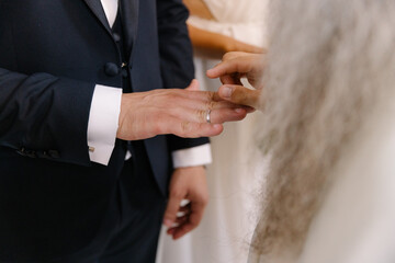 Naklejka premium Close-up of a bride putting the wedding ring on the groom's finger during the marriage ceremony