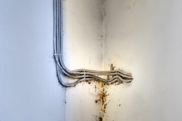 Close-up of electrical cables improperly embedded in wall plaster, violating safety standards