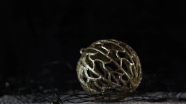 Una toma de cerca de una bola de navidad dorada rodeados de luces blancas con un fondo desenfocado. Decoraci&oacute;n de navidad y fin de a&ntilde;o
