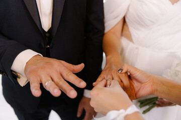 Close-up of a groom and bride exchanging wedding rings during the marriage ceremony, symbolizing their eternal love and commitment
