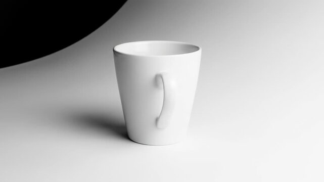 A white ceramic mug with a curved handle sits on a light surface. The background transitions from bright to dark. A shadow is cast