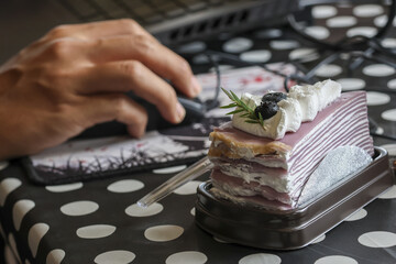 Hand using computer mouse, actively working laptop. delightful sweet crepe cake dessert provides an indulgent food break. This delicious treat, with blueberries and whipped cream, offers contented