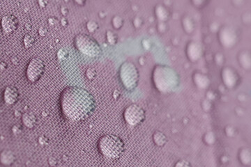 Water droplets gently rest pink textile fabric, beautifully illustrating its waterproof and water repellent surface. This close up captures delicate texture, highlighting protective barrier