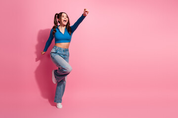 A cheerful young woman celebrates with an excited gesture against a vibrant pink background,...