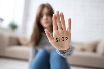A young woman extends her hand with the word 'STOP' written on it, symbolizing the importance of setting boundaries and advocating for personal space in today's society.