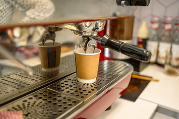 Coffee machine pouring coffee into a paper cup, close up
