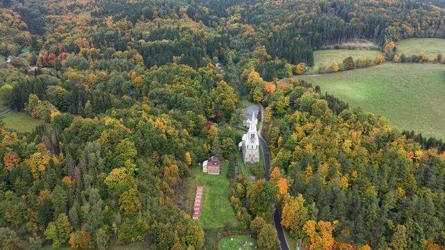 Aerial valley village church Travna Czechia autumn circle 3 4K. The Czech Republic or Czechia historically known as Bohemia. Central Europe. Autumn fall season, brilliant colorful leaves along roads.