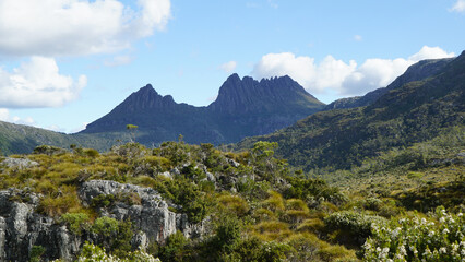 Majestic mountain peaks rise above a rugged, green landscape under a clear blue sky. © Sophia Bennett