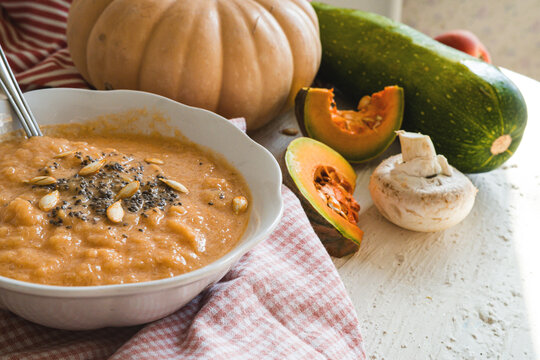 Pumpkin is a superfood. A pumpkin soup is a healthy food. It is healthy and nutritious food for autumn. A vitamin made from pumpkin and other vegetables on a rustic background.