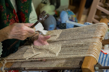 Skilled artisan weaving natural fibers on traditional loom with intricate craftsmanship and focus