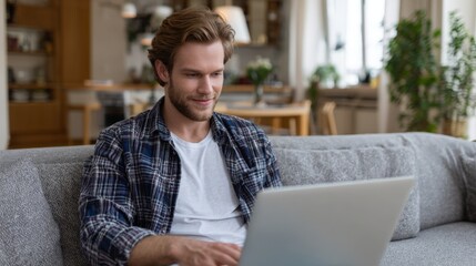 Fototapeta premium Young caucasian male working on laptop in cozy home setting