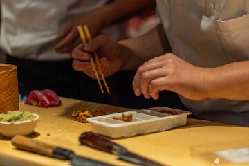 Obraz premium Skilled chef preparing sushi with chopsticks in a vibrant kitchen setting