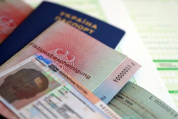 German Permanent resident card and document specimen lies with Ukrainian passport on tax form close up. Aufenthaltstitel and Fiktionsbescheinigung