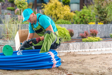 Gardener Working With Blue Tubing in a Landscaped Area