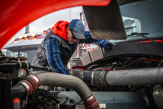 Caucasian Mechanic Checks Engine in Heavy Truck During Overcast Day - Powered by Adobe