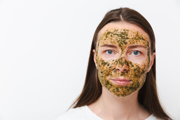 Portrait of young girl or woman with green natural homemade cosmetic mask on her face on a white background. Concept of self-care at home or in salon. Copy space