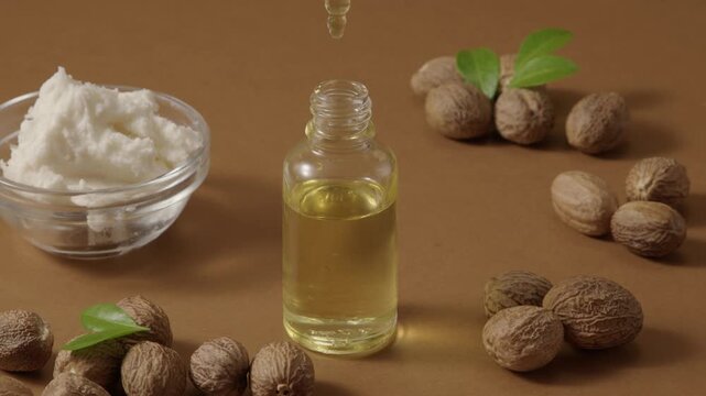 Shea butter bottle placed next to avocado and nuts, each drop of nutritious oil drips onto the bottle mockup for design