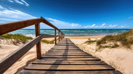 Obraz premium Wooden walkway leads to sandy beach and ocean under a clear blue sky on a sunny day