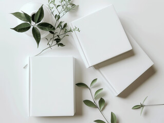 Minimalist flat lay features clean white notebooks and delicate green branches, perfect for creative projects and branding mockups.