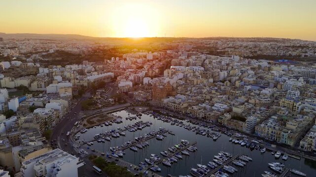 Drone flight at sunrise over the yachts towards St. Joseph&rsquo;s Church, Msida. Valletta, Malta