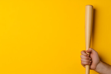 A hand gripping a wooden baseball bat against a vibrant yellow background. The bat's smooth texture contrasts with the bright, solid color, creating a simple, eye-catching image.