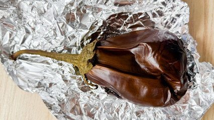 Roasted aubergine cocooned in shimmering foil, echoing Mediterranean harvest feasts and rustic...