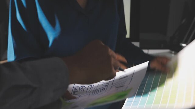 Group of young Asian uxui designers working together pointing at computer screen analyzing mobile app interface wireframes while working in a modern office