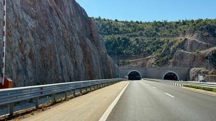 Sunlit highway tunnels burrow through rocky cliffs, echoing traveler's wanderlust and Earth Day's ode to nature's marvels