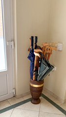 Elegantly rustic umbrella stand holds eclectic walking canes and umbrellas, evoking cozy hearthside...